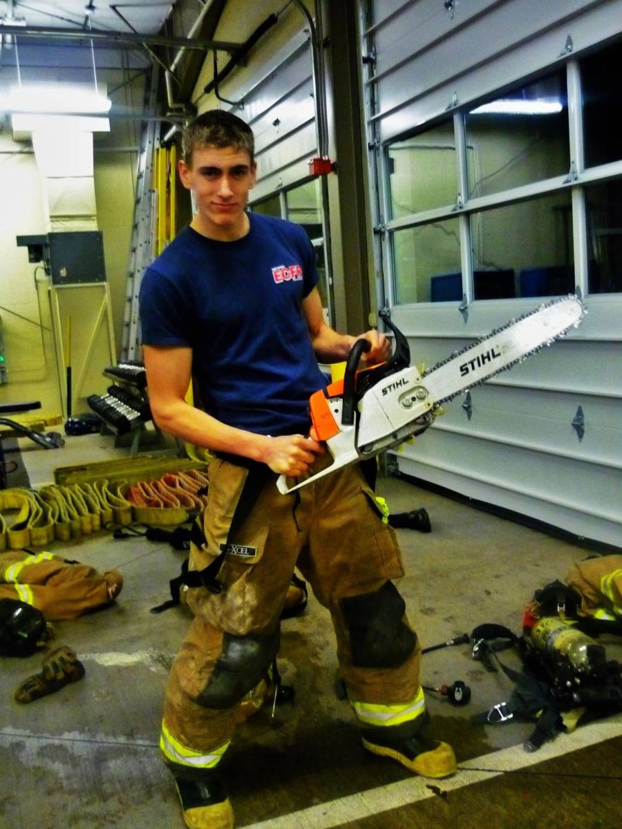 Nathaniel as a firefighter at the station with a chainsaw
